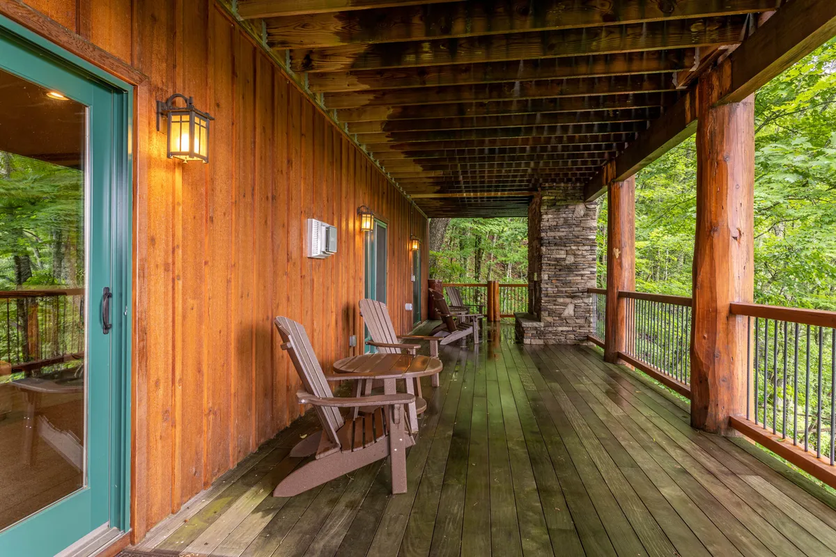 A tranquil outdoor deck with comfortable seating and a robust stone pillar supporting a fireplace. Lanterns and rustic touches create a cozy extension of the indoor living space, with views perfect for stargazing or sharing stories outdoors.