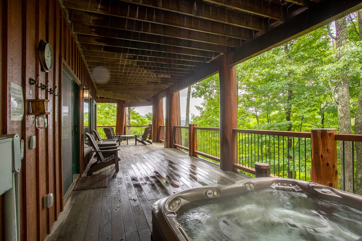 A tranquil outdoor deck featuring a private hot tub and comfortable seating, set against a backdrop of trees. The view highlights the peaceful environment and the promise of relaxation after a day of adventure.