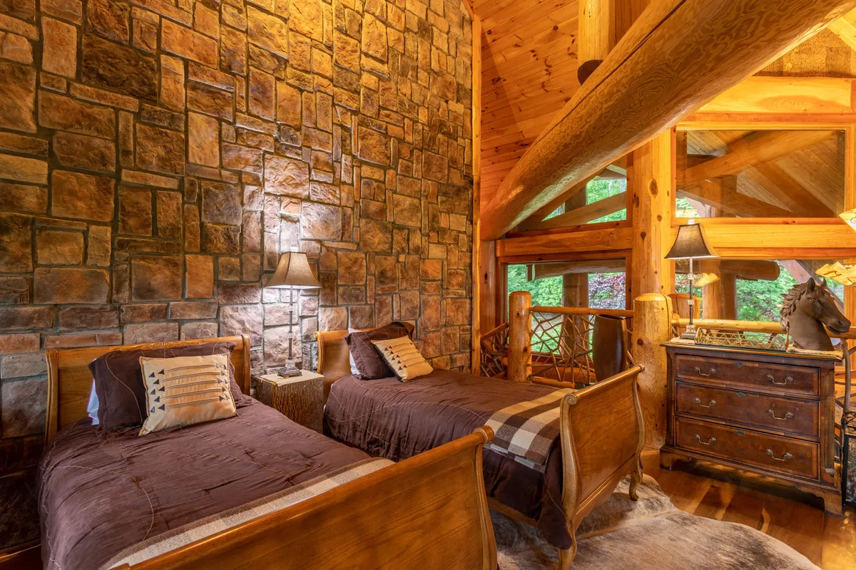 A rustic yet inviting bedroom with wooden twin beds, a stone accent wall, and a decorative lamp. The setting is perfect for younger guests or extra family, with cozy bedding and a sense of togetherness.